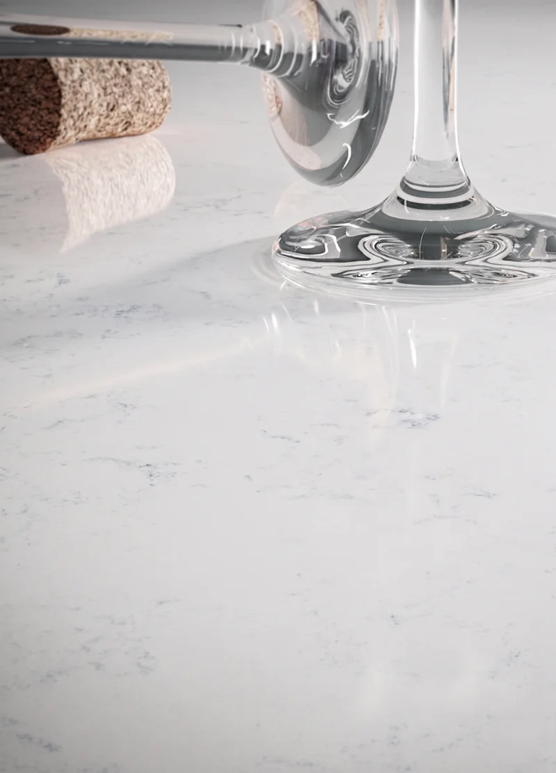 Verre à pied posé sur un quartz poli : le reflet net du pied se lit dans la surface miroir